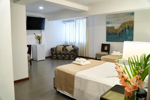 a hotel room with two beds and a couch at Hotel Marcoantonio - Moyobamba in Moyobamba