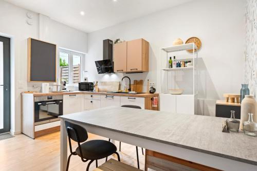 une cuisine avec des armoires blanches et une table et des chaises dans l'établissement Maison Calme avec Jardin - 10 pers - Proche Centre Rouen, à Rouen