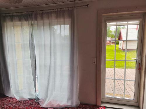 a window with a white curtain next to a door at Elly Kodumajutus Kihnus in Linaküla