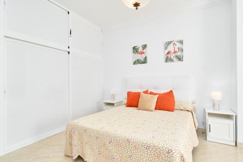 a white bedroom with a bed with orange pillows at Animas Duplex in Nerja