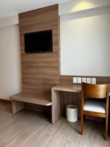 a room with a flat screen tv and a chair at Vista Azul Apart Hotel - Suítes com vista para a mata de pinheiros in Pedra Azul