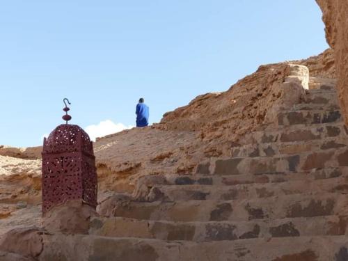 a man sitting on top of a hill with a cross at Campement Akka Nait Sidi - Tissint in Tissint