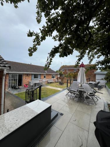 a patio with chairs and a table with an umbrella at Bungalow with hot tub & Sauna in Kingsgate