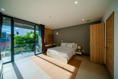 a bedroom with a bed and a large window at Sila Anila 7BRs Pool Villa My Khe Beach Da Nang in Da Nang