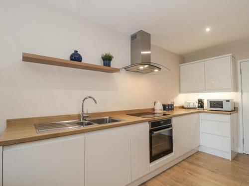 a kitchen with white cabinets and a sink at Royal Terrace Sunset in Weymouth