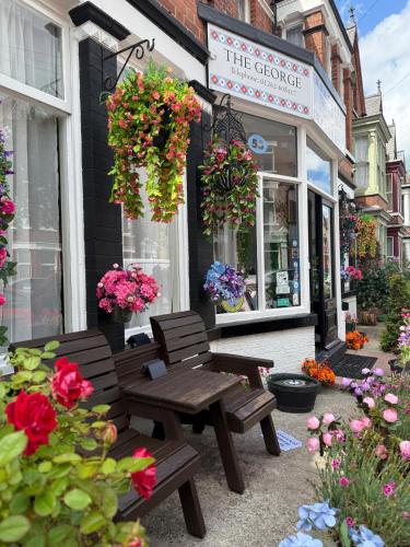 a bench and flowers in front of a store at The George Guest House in Bridlington