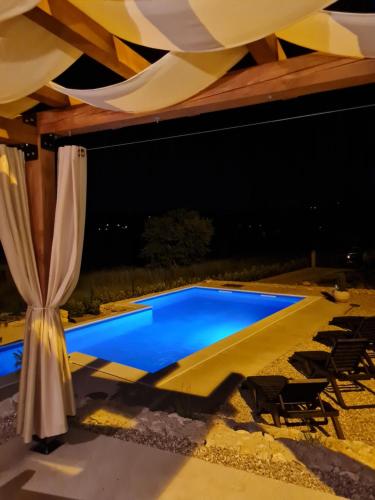 a swimming pool at night with a tent and chairs at Kamena kuća Goranci in Mostar