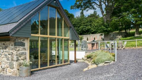 a large glass house with a stone wall at Bwthyn Ysgubor in Conwy