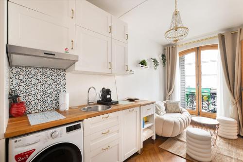 une cuisine avec des armoires blanches et un évier dans l'établissement Haussmannian elegance close to Montmartre, à Paris