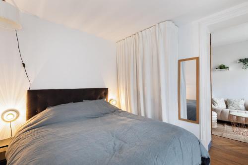 une chambre avec un grand lit et un miroir dans l'établissement Haussmannian elegance close to Montmartre, à Paris