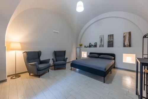 ein Schlafzimmer mit einem Bett und zwei Stühlen in der Unterkunft House Mandarino in Bari