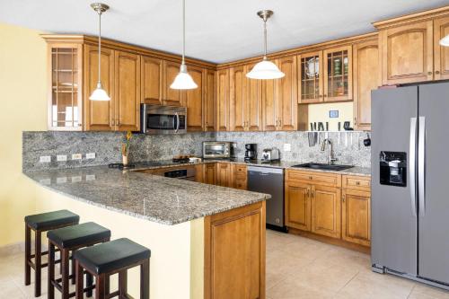 a kitchen with wooden cabinets and a granite counter top at Cheerful Seascape Condo Happy Haven at Rainbow Beach Club in Cupe Coy