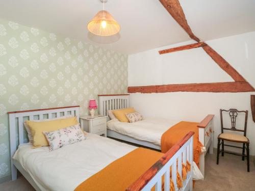 a bedroom with two beds and a chair at Old Farm Cottage in Warminster