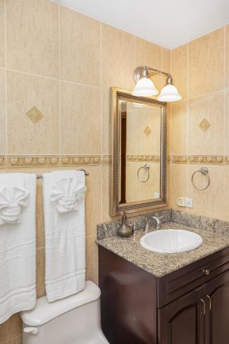 a bathroom with a sink and a toilet and a mirror at Cheerful Seascape Condo Happy Haven at Rainbow Beach Club in Cupe Coy