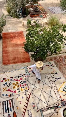 a man in a hat standing on a pile of rug at Agafay Desert Hotel in El Karia