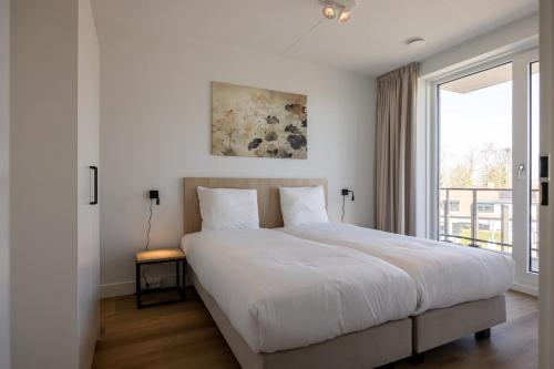 a white bedroom with a large bed and a window at Apartment Havenzicht 8a Kortgene in Kortgene