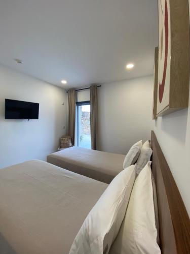 a bedroom with two beds and a flat screen tv at Casas de Campo Curral Grande - By Cimo da Quinta in Pena Branca