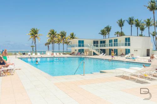 a swimming pool with palm trees and a building at Girasole Rentals Suites in Miami Beach