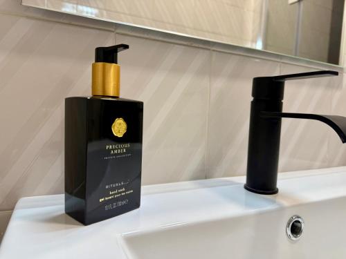 a black bottle of soap sitting on a bathroom sink at GOLDEN VILLA by Stay in Alentejo in Vila Nova de Milfontes