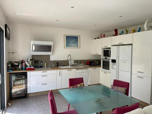 a kitchen with white cabinets and a glass table at Maison familiale avec piscine à Juvignac, 90 m², 6 pers. in Juvignac