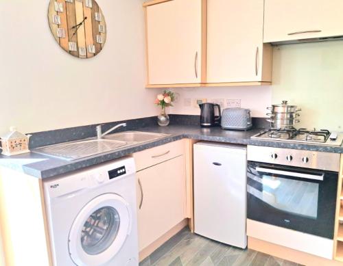 a kitchen with a washing machine and a sink at Heather Lea townhouse in Bebside