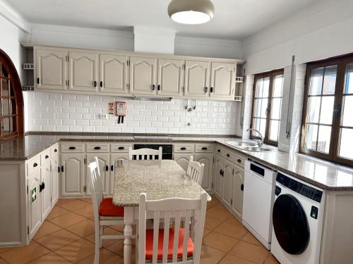 a kitchen with white cabinets and a table and chairs at GOLDEN VILLA by Stay in Alentejo in Vila Nova de Milfontes
