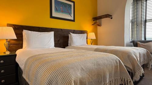 two beds in a bedroom with yellow walls at Watermead House in Chard