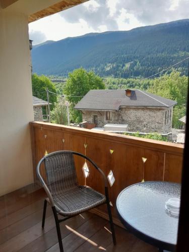 a table and a chair on a balcony with a view at Bapsha Guesthouse in Mestia