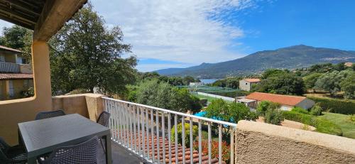 d'un balcon avec une table, des chaises et des montagnes. dans l'établissement T2 Résidence Dolce & Vita B4 vue mer et piscine, à Propriano