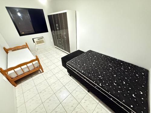 a bedroom with a bed and a tv and a tiled floor at Pé na areia canto do forte VI in Praia Grande