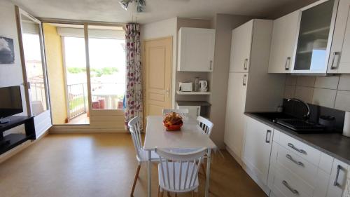 une cuisine avec une table et des chaises et une fenêtre dans l'établissement Saint Pierre la mer - Les Sénillades - T2 cabine proche de la grande plage, à Saint Pierre La Mer