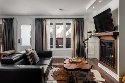 a living room with a black couch and a fireplace at Chic condo at the foot of the slopes of Saint-Sauveur in Saint-Sauveur-des-Monts