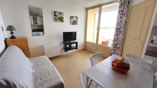 un salon avec une table et une télévision dans l'établissement Saint Pierre la mer - Les Sénillades - T2 cabine proche de la grande plage, à Saint Pierre La Mer