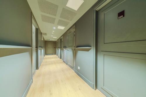 an empty hallway with doors and wood floors at Babel Community Hôtel - Montpellier centre in Montpellier