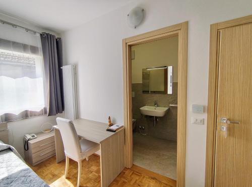 a bedroom with a desk and a bathroom with a sink at Hotel Da Marco in Vigo di Cadore