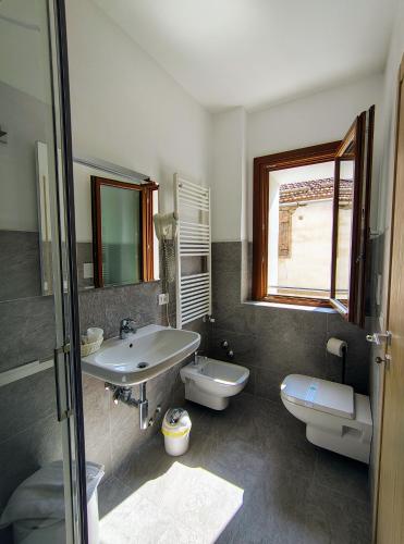 a bathroom with a sink and a toilet and a window at Hotel Da Marco in Vigo di Cadore