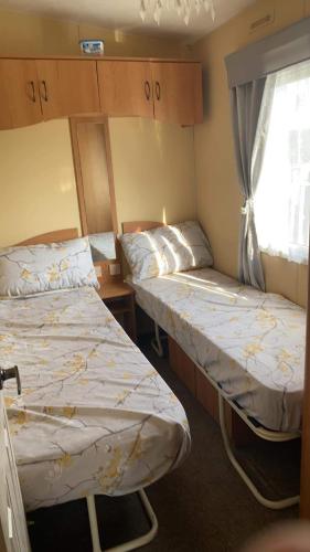 two beds in a small room with a window at Pet Friendly Location Close To Beach in Ingoldmells