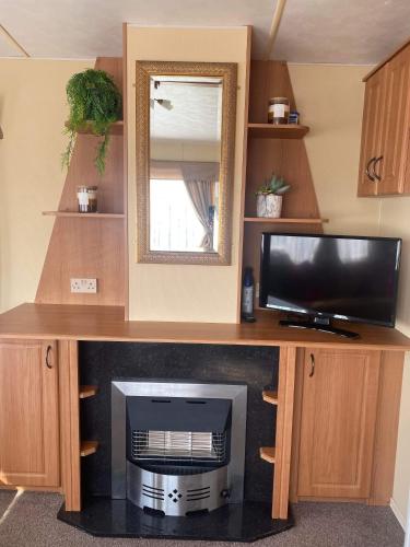 a desk with a television and a mirror at Pet Friendly Location Close To Beach in Ingoldmells