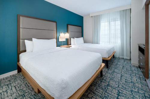 two beds in a hotel room with blue walls at Homewood Suites by Hilton Eatontown in Eatontown