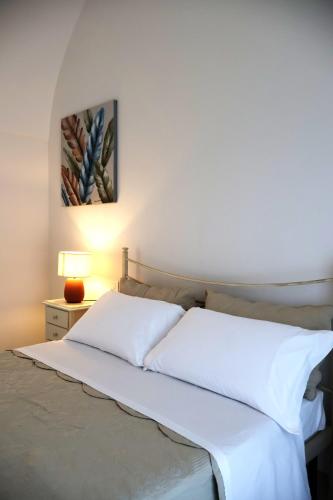 a bedroom with a bed with white sheets and a lamp at IL CARRUBO La dimora in Monopoli
