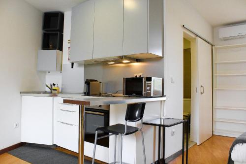 a kitchen with white cabinets and a counter with a microwave at São Pedro City Flat in Vila Real