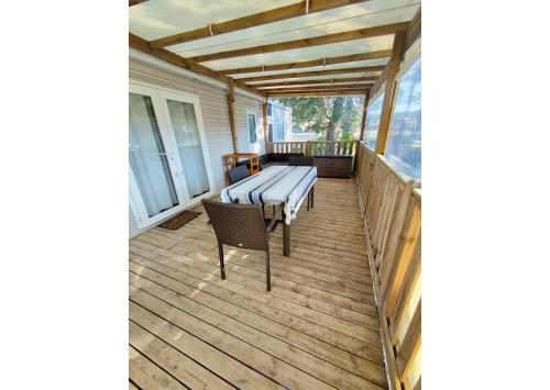 un porche grillagé avec un banc sur une terrasse dans l'établissement Mobil-home Clim, TV, LV Camping LES OYATS 4 étoiles - MH-A017, à Seignosse