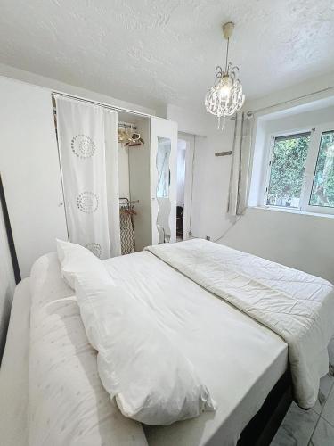 une chambre avec un grand lit blanc avec un lustre dans l'établissement Paisible deux pièces, à Cannes