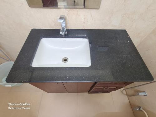 a black counter top with a white sink in a bathroom at Home stay in Kondapur