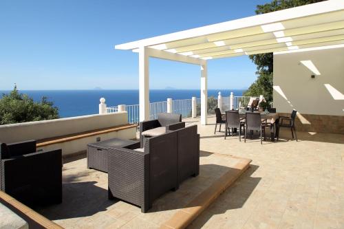 a patio with a table and chairs under a pergola at Villa DAMMUSO by Local House - private villa infinity pool & seaview in Santo Stefano di Camastra