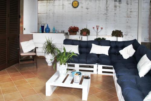 a living room with a blue couch and plants at Villa DAMMUSO by Local House - private villa infinity pool & seaview in Santo Stefano di Camastra