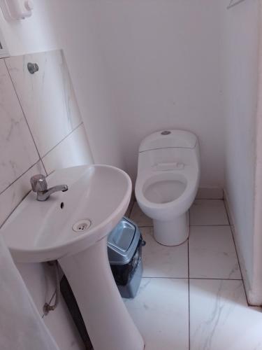 a white bathroom with a toilet and a sink at Casa Duna Sur in Huacachina