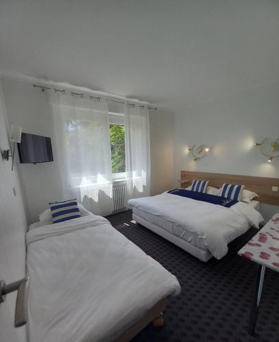 une chambre avec deux lits et une fenêtre dans l'établissement Les nouveaux Ambassadeurs, à Saint-Chamond