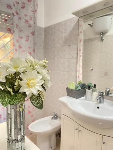 a bathroom with a sink and a vase with flowers in it at Casa Linda in Lido di Ostia