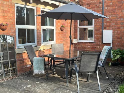 ein Tisch mit Stühlen und einem Sonnenschirm auf einer Terrasse in der Unterkunft Hanley Swan, The Garden Flat in Madresfield